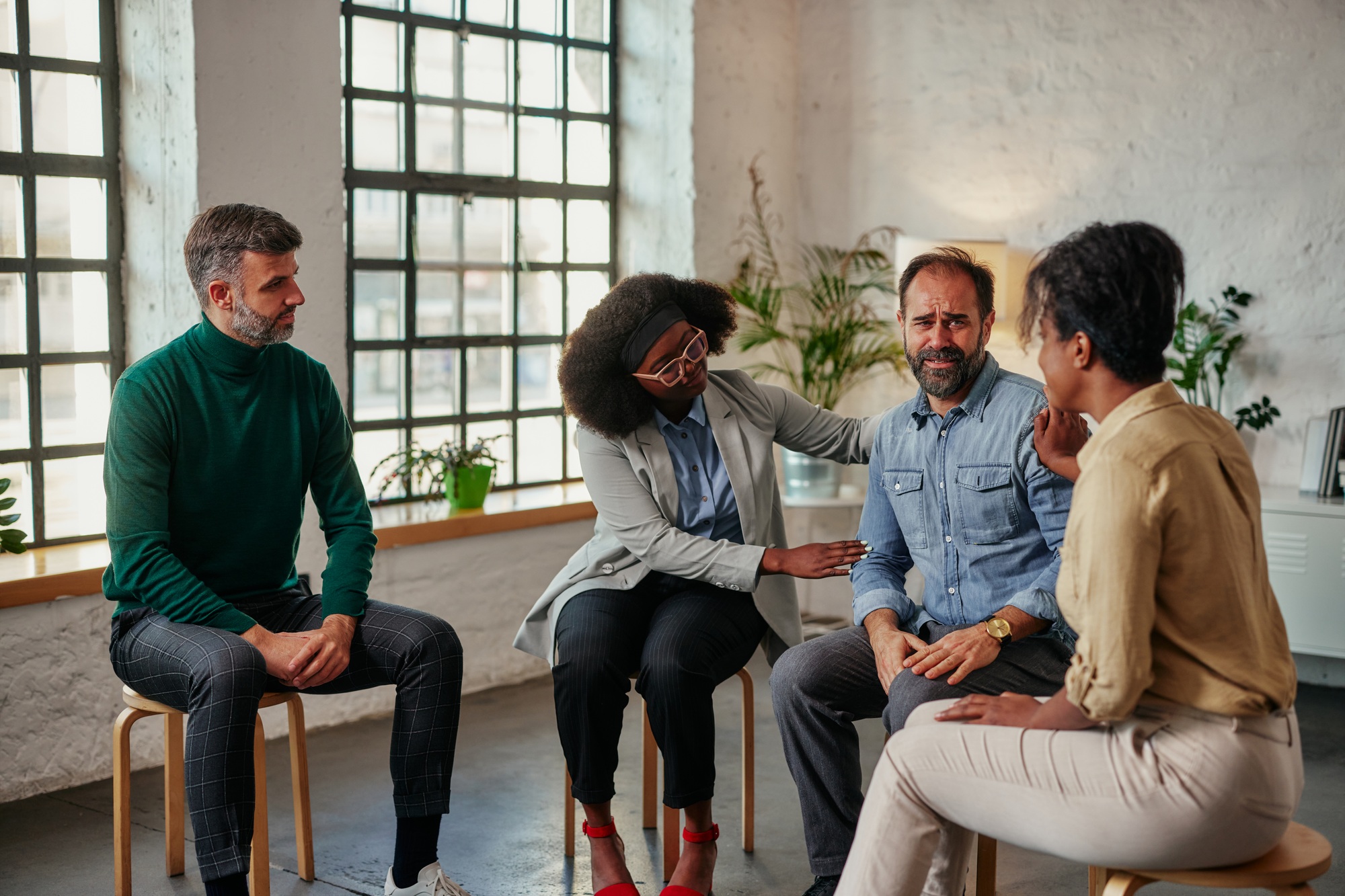 Support group patients comforting man at therapy session